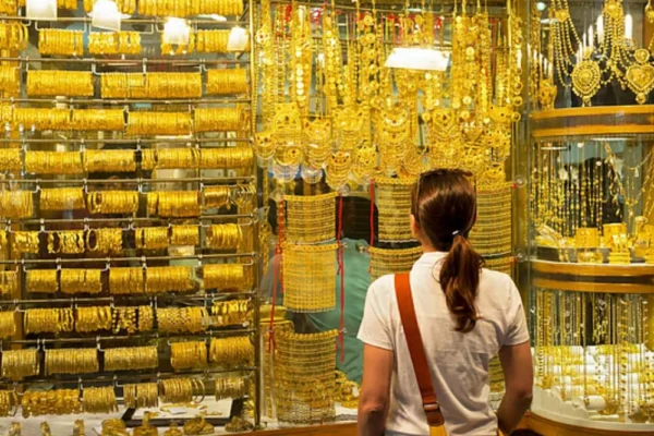 Woman standing outside a jewellery shop in Dubai showcasing UAE gold jewellery offers despite high gold prices.